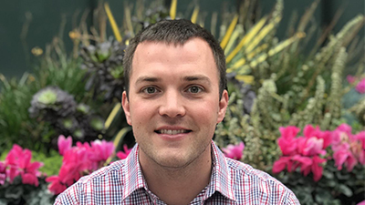 a man smiling in front of a flower garden