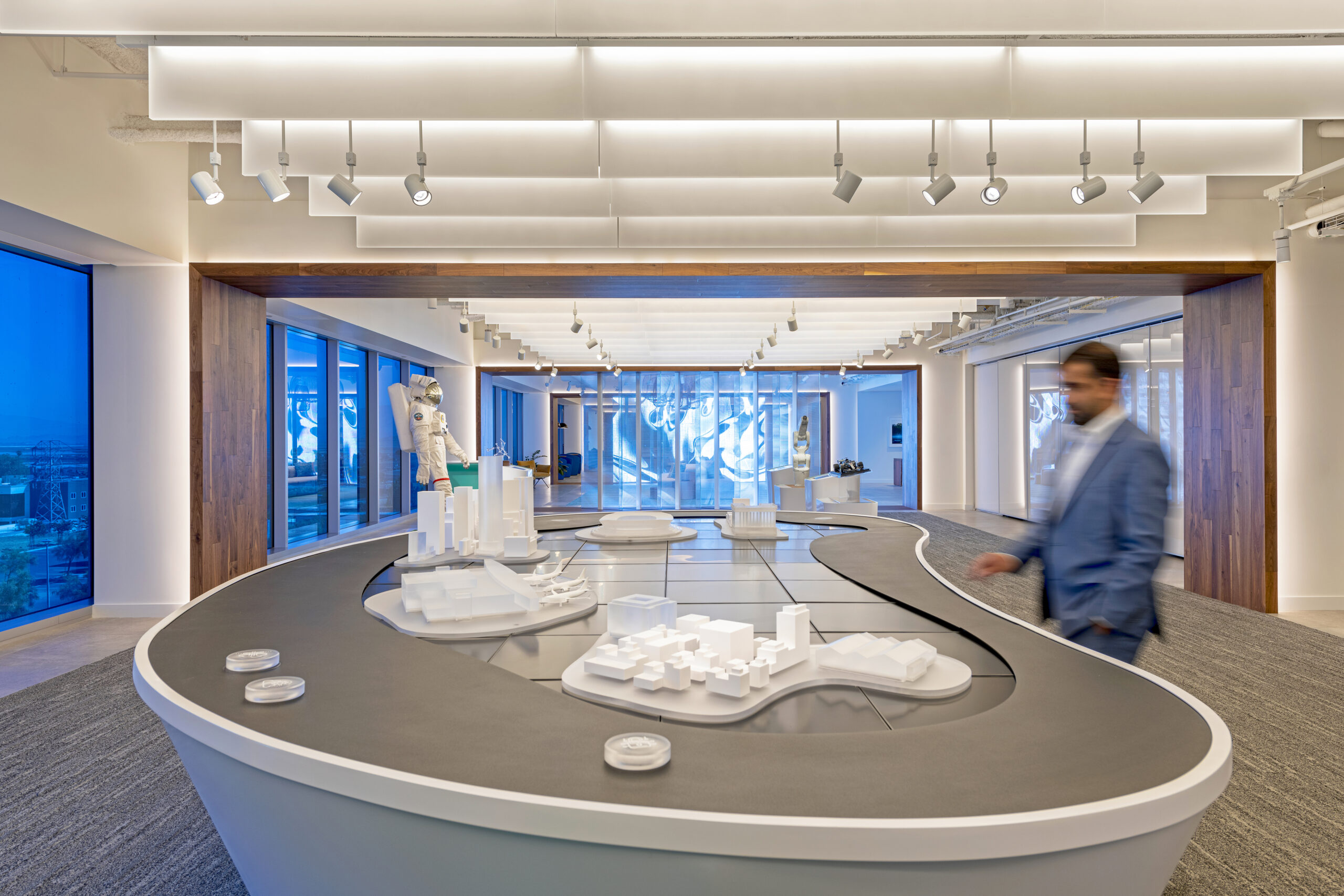 a person in a blue coat looking at an architectural model