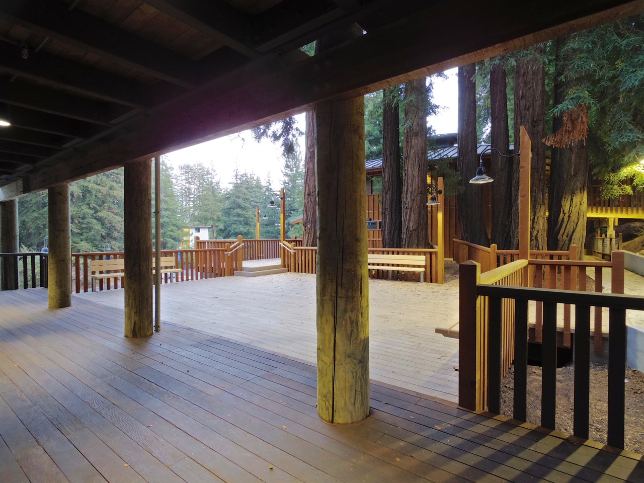 a wood deck with a wood railing with trees and plants