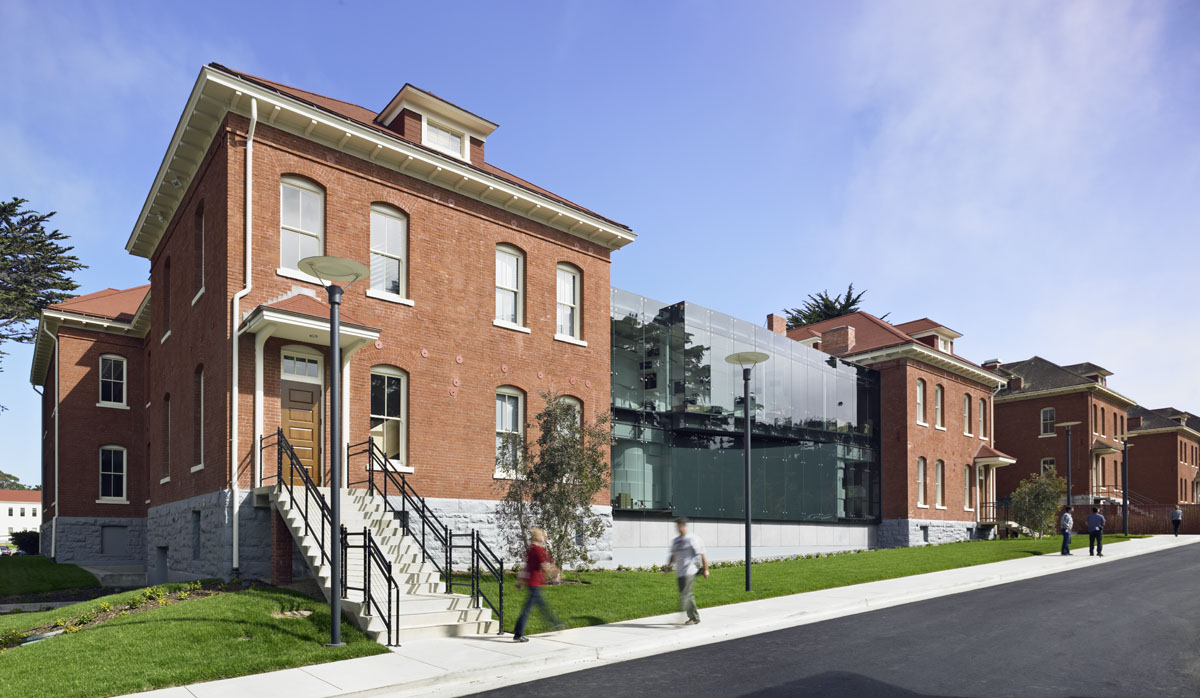 a brick building with a street and people walking on the sidewalk