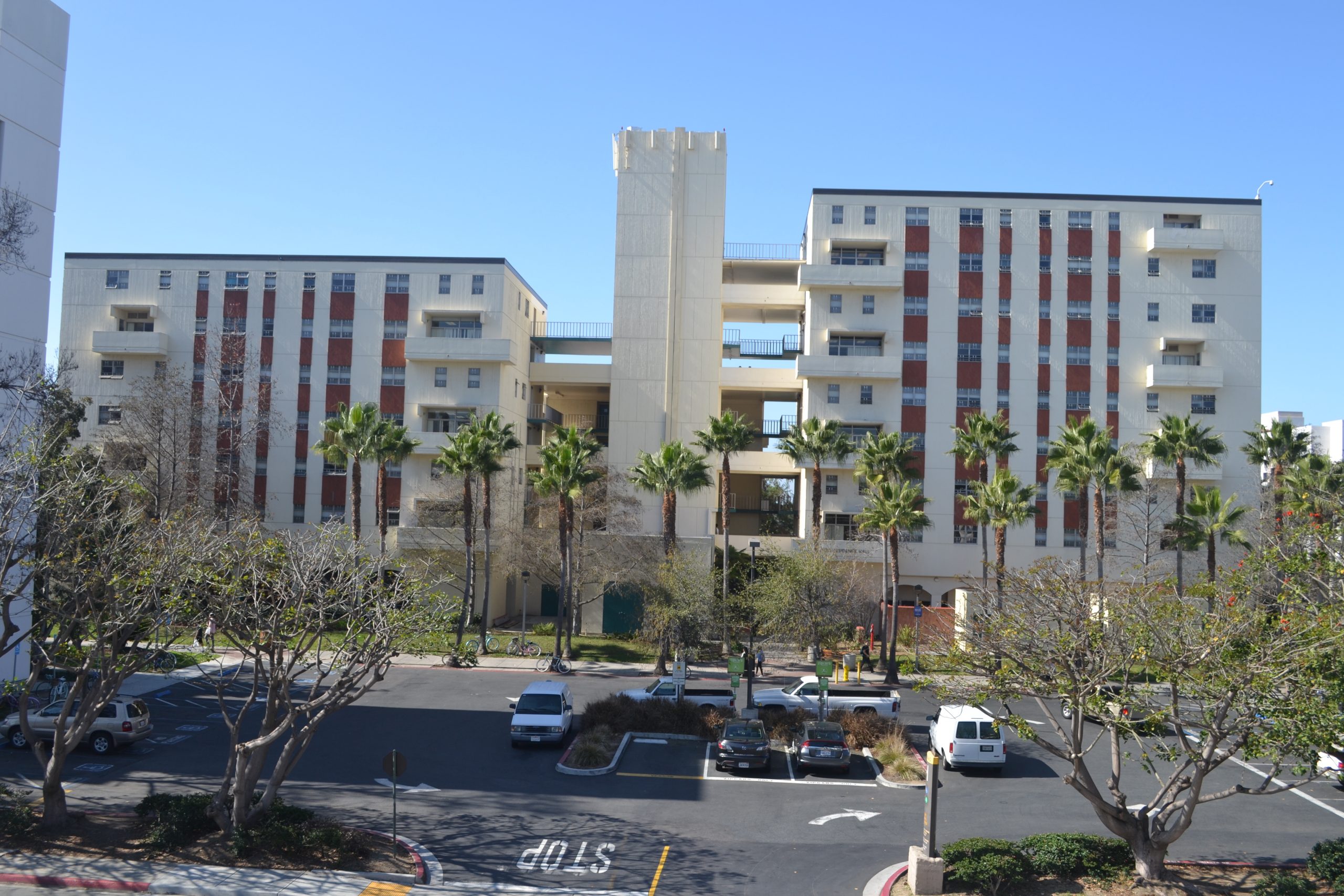 a parking lot with cars and trees in front of a building